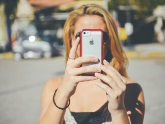 Frau hält Smartphone in die Kamera
