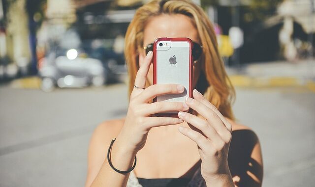 Frau hält Smartphone in die Kamera